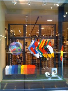 a window display with soccer balls and flags in the front, behind which is a goal net