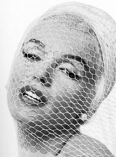 a black and white photo of a woman's head with netting covering her face