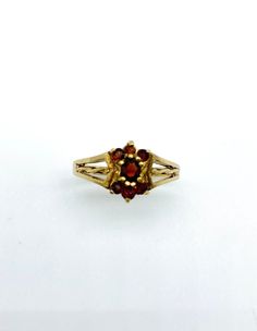 Description: Elegant beautifuly crafted Garnet Dress Ring. One central garnet surrounded by six smaller garnets and set in a beutifully made 9ct gold mount Metal: 9ct Yellow Gold Size: UK M1/2/ E.U 53/ U.S 6.5 Weight: 2.62gms Condition: Very Good Vintage Condition.  Notices: 1)Manufacture: Butterfly Rock VC is not the manufacturer. Items are sourced via a third party and as such we used the description of the item as it was presented to us. 2)Warranty: No warranty is given on this item. 3)Metal Finesse: If it is not otherwise stated then the quality/grade of the material is unknown. 4)Gemstones: Items containing gemstones are often treated to enhance colour or clarity. This has not been examined for this specific item.    5)Please see photos to assess the condition for yourself. We do not Vintage Yellow Gold Garnet Birthstone Ring, Vintage Garnet Birthstone Ring In Yellow Gold, Vintage Gold Garnet Birthstone Ring, Vintage Garnet Birthstone Rings, Vintage Oval Garnet Birthstone Ring, Vintage Garnet Birthstone Ring For Anniversary, Formal Gold Garnet Birthstone Ring, Vintage Gold Ruby Cluster Ring, Vintage Gold Cluster Ruby Ring