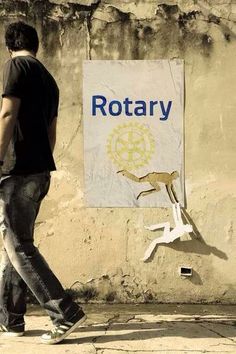 a man walking past a rotary sign on the side of a building with a kangaroo painted on it