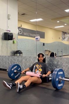 a woman sitting on the ground with a barbell