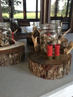 two mason jars filled with coins sitting on top of a wooden log next to a window