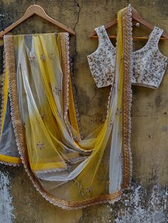 This ivory butti georgette lehenga is paired with an ivory embroidered raw silk blouse.  The outfit is complemented with a net yellow and ivory shaded dupatta with a scalloped border. Yellow Organza Pre-draped Saree For Reception, White Organza Sets With Gota Work, Yellow Anarkali Style Organza Pre-draped Saree, Yellow Organza Sharara With Intricate Embroidery, White Tissue Silk Lehenga With Cutdana Details, White Tissue Silk Lehenga With Cutdana, White Tissue Silk Lehenga With Pallu, Yellow Dupatta With Cutdana For Reception, White Tissue Silk Choli With Pallu Detail