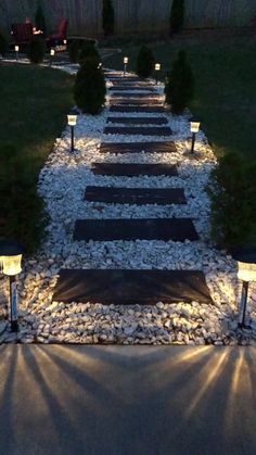 an outdoor path with lights and gravel in the middle, leading to a grassy area