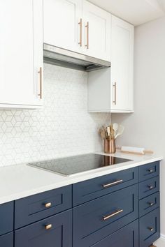 a kitchen with white and blue cabinets and gold pulls on the cabinet doors, along with brass knobs