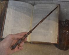 a person holding an old book with a wand in it