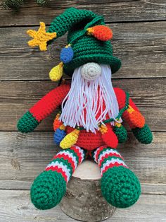 a crocheted gnome sitting on top of a tree stump