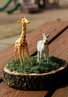 two toy giraffes and a zebra on top of a tree stump