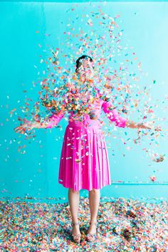 a woman in a pink dress surrounded by confetti and sprinkles