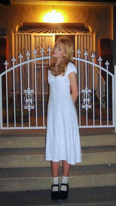 a woman standing in front of a white gate