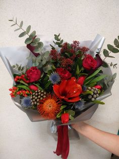 a bouquet of flowers is being held by someone's hand on a white surface