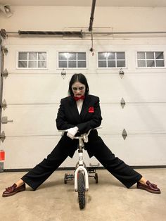 a woman sitting on top of a bike in front of a garage door