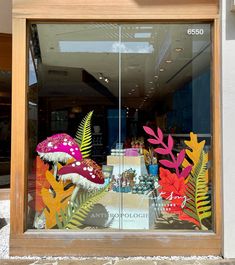 a store window with an assortment of fake plants in the front and behind it is a display case