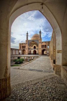 an archway leading to a large building with two towers on each side and a courtyard in the middle