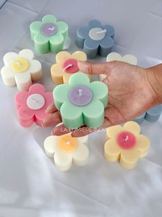 a hand is holding several candles with flowers on them