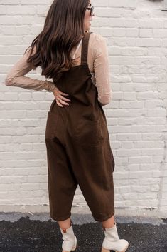 Step into effortless style with the Bridget Denim Overall Jumpsuit. Made from durable denim fabric, this jumpsuit features wide-leg pants and two front cargo pockets for a utilitarian touch. The square neckline and adjustable straps ensure a comfortable fit, while black drawstring details add a trendy, playful element. Available in cream or dark brown, the Bridget Jumpsuit is a versatile piece that can be dressed up or down for any occasion. Utility Overalls With Patch Pockets, Utility Overalls With Patch Pockets And Bib Front, Brown Cotton Overalls For Spring, Fall Cotton Shortalls In Relaxed Fit, Utility Overalls With Adjustable Straps For Workwear, Cotton Shortalls With Relaxed Fit For Fall, Utility Straight Leg Jumpsuits For Workwear, Utility Style Workwear Jumpsuits With Straight Leg, Utility Workwear Jumpsuit With Straight Leg