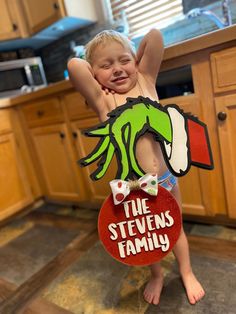 a young boy holding up a cut out of the grin face on top of his head