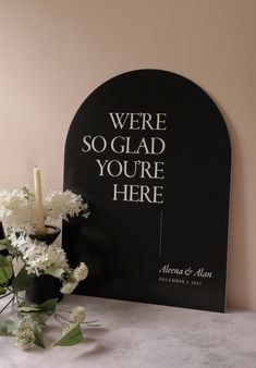 there is a vase with flowers next to a sign that says we're so glad you're here