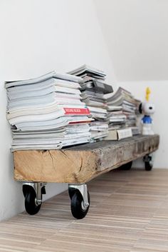 a pile of papers sitting on top of a wooden table next to a white wall