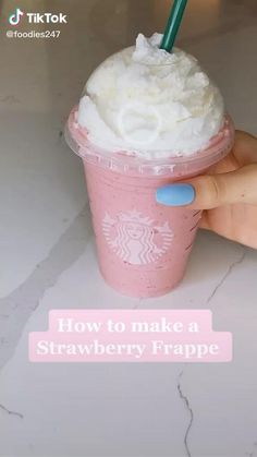 a hand holding a pink starbucks drink with whipped cream on top and the words how to make a strawberry frappe