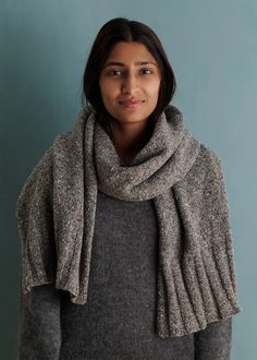 a woman wearing a gray sweater and scarf