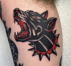 a black and red tattoo on the arm of a man with an angry wolf head