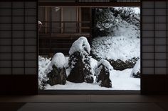 an open door with snow on the ground and rocks in front of it that are covered in snow