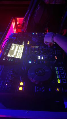 a dj playing music in front of some neon colored lights at a nightclub or club