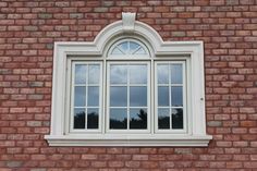 a brick wall with an arched window and white trim