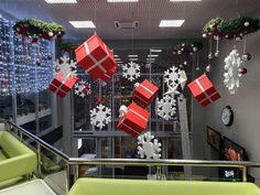 christmas decorations hanging from the ceiling in an office building with snowflakes and presents