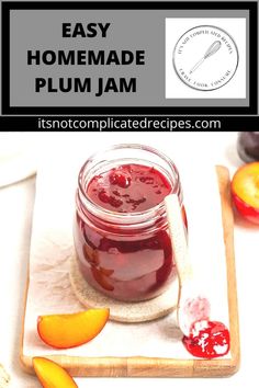 homemade plum jam in a glass jar on a cutting board next to sliced peaches