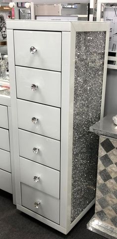 a white dresser sitting next to a mirror on top of a counter in a store