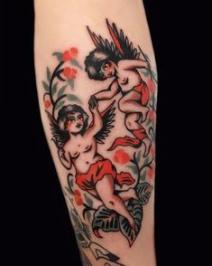 an artistic tattoo on the leg of a woman with red flowers and two cherubs