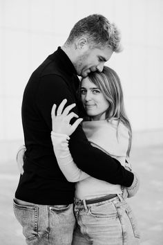 a man and woman hugging each other in black and white