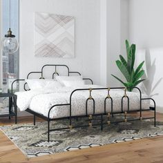 a white bed sitting on top of a wooden floor next to a green potted plant