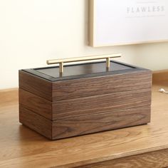 a wooden box sitting on top of a table next to a framed photograph and a gold handle