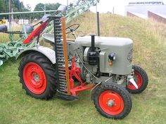 an old farmall tractor is parked on the grass near a fence and other equipment