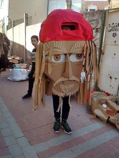 a cardboard man with a red hat and dreadlocks standing in front of a building