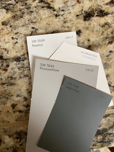 some white and gray paint samples on a granite counter top with the same color swatches