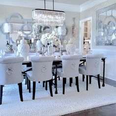 a dining room table with white chairs and chandelier