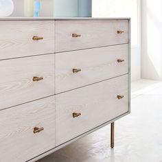 a white dresser with brass handles in a room