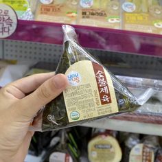 a person holding up a bag of food in front of a shelf with other items