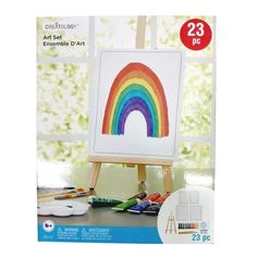 an easel with paint and pencils on it in front of a window that has the image of a rainbow painted on it