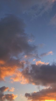 the airplane is flying high in the sky at sunset or dawn, with some clouds above it