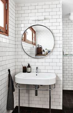 a white sink sitting under a round mirror in a bathroom