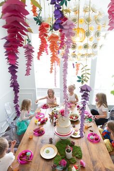 a group of children sitting around a wooden table with plates and cake on top of it