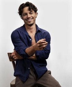 a man sitting on top of a wooden chair with his arms crossed in front of him