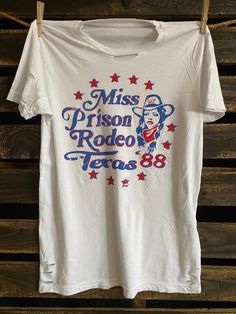 Country Deep Miss Prison Rodeo Texas 1988 vintage unisex distressed T shirt in vintage wash white Throw back vintage tee from the Bakersfield prison rodeo 1988 40 Singles Jersey 100% Cotton Premium quality ringspun and compacted cotton Fine Cotton Jersey that is pigment dyed for a more vintage look Features tears and destroyed features at neck and on body Each piece is unique as this process is done by hand! 3.8 oz Made In USA Every garment dye item can be a slightly different shade in color sin Vintage Crew Neck Top For Rodeo, White Short Sleeve T-shirt For Rodeo, White Crew Neck T-shirt For Rodeo, White Screen Print T-shirt For Rodeo, Vintage Letter Print Tops For Rodeo, White Graphic Print Shirt For Rodeo, Retro Rodeo T-shirt With Screen Print, Vintage Relaxed Fit T-shirt For Rodeo, Retro Rodeo Crew Neck T-shirt