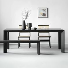 a black table with two chairs and a bench next to it in front of a white wall