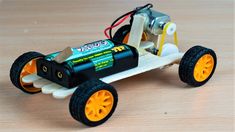 a toy car made out of plastic with wheels and batteries on the front, sitting on a wooden surface